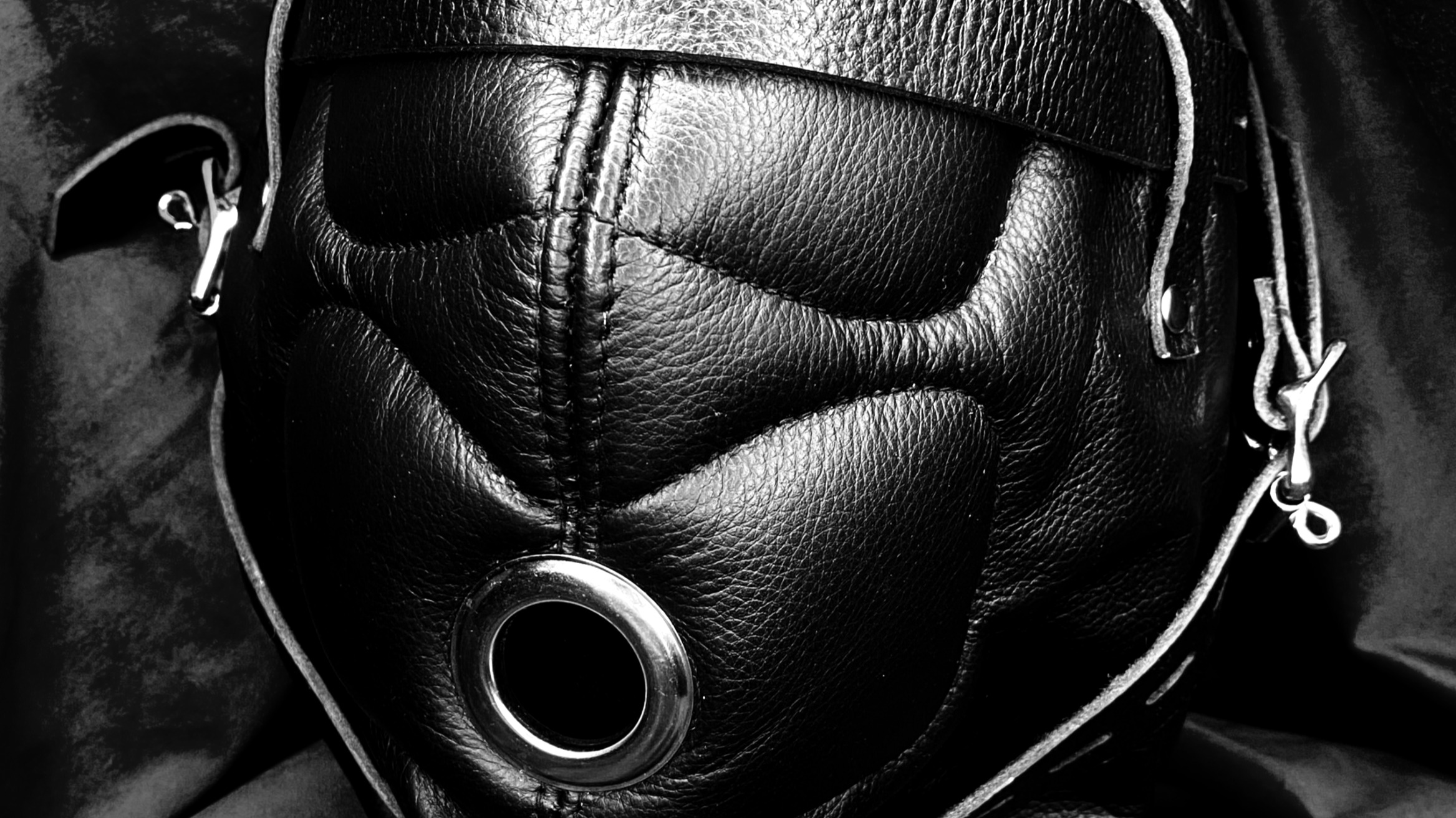 Close-up black and white photograph of Mistrix Violeta's black leather sensory deprivation hood